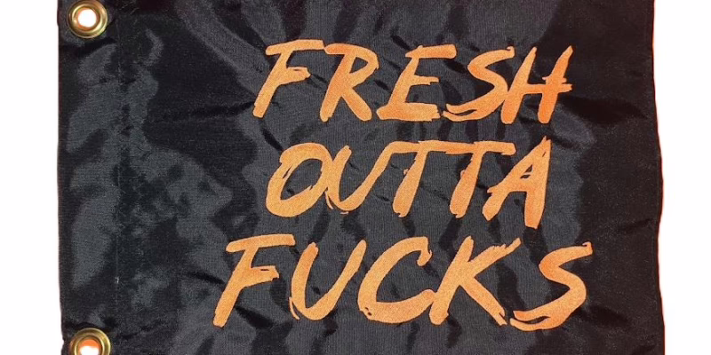 Fresh Outta Fucks safety flag with orange embroidered brush lettering on black nylon rectangle