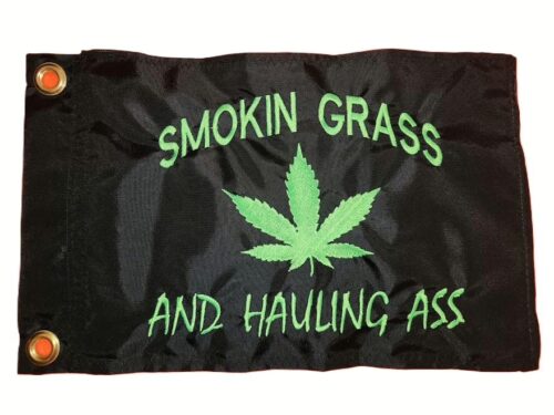 Smokin grass and hauling ass safety flag with dense embroidered green text and cannabis leaf on black nylon rectangle with solid brass grommets
