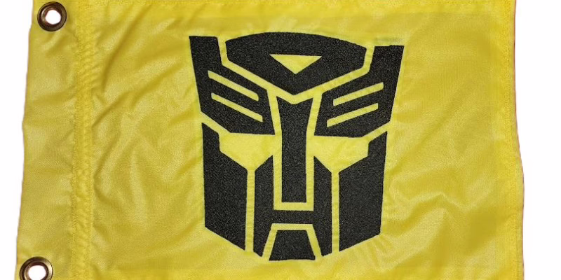 Transformers Autobot safety flag with dense embroidered black faction crest on yellow nylon rectangle with solid brass grommets