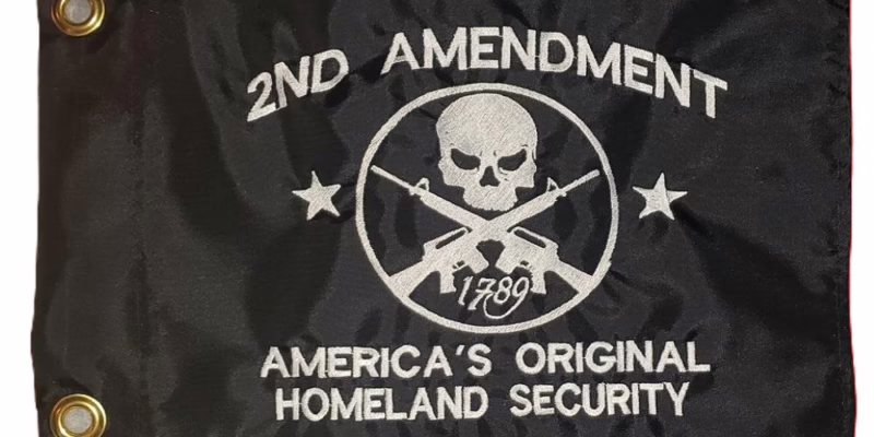 2nd amendment safety flag with dense embroidered white skull and crossed rifles on black nylon rectangle with solid brass grommets