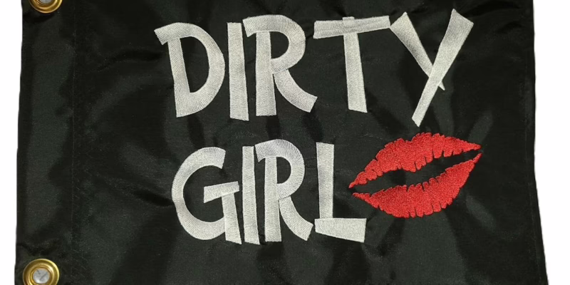Dirty Girl safety flag with dense embroidered white text and red lips on black nylon rectangle with solid brass grommets
