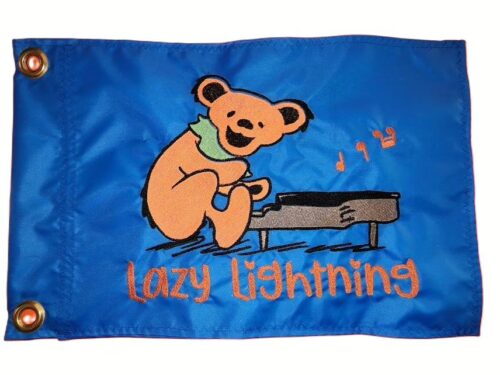 Grateful Dead piano bear safety flag with embroidered orange bear playing piano and Lazy Lightning text on bright blue nylon rectangle with brass grommets