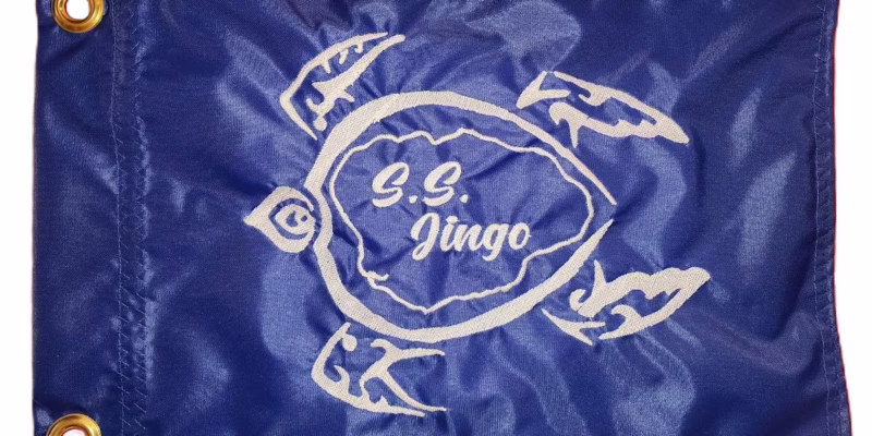 Sea Turtle safety flag with white embroidered petroglyph turtle and S.S. Jingo text on royal blue nylon rectangle with brass grommets