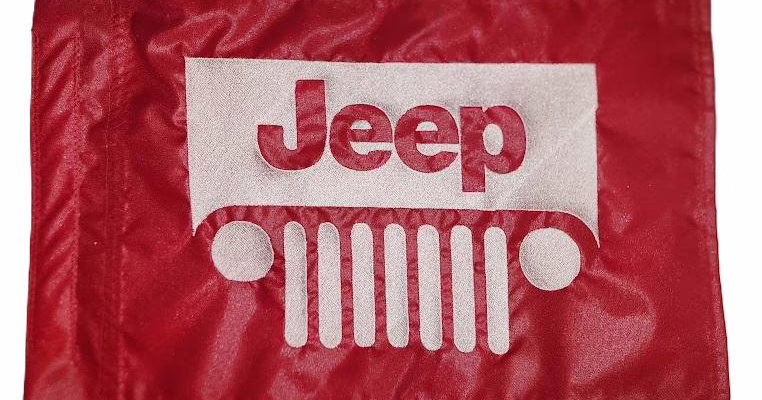 Jeep safety flag with embroidered white seven-slot grille and logo on red nylon rectangle with whip sleeve