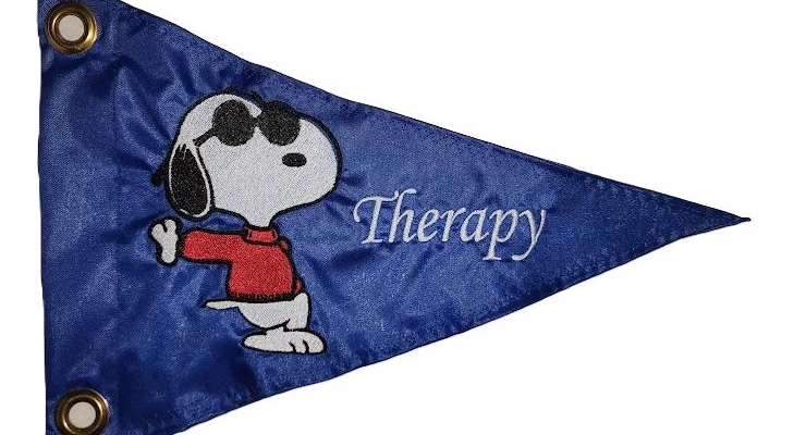 Snoopy safety flag with embroidered dog wearing sunglasses and red sweater with Therapy text on royal blue nylon pennant with brass grommets