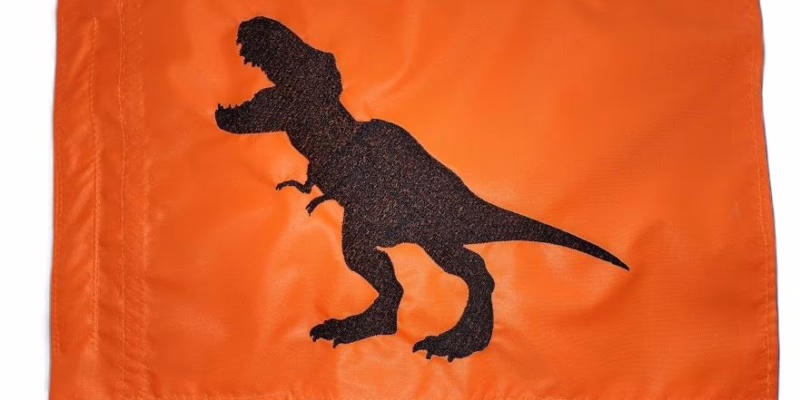 T-Rex dinosaur safety flag with dense embroidered black tyrannosaurus rex silhouette on vibrant orange nylon rectangle with whip sleeve