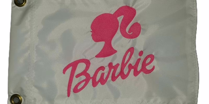 Barbie doll silhouette safety flag with dense embroidered ponytail head and cursive script on nylon rectangle with brass grommets