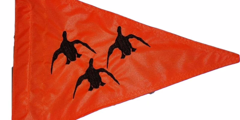 Fluorescent orange triangle safety whip flag featuring dense embroidered silhouettes of three flying mallard ducks on heavy-duty nylon with a reinforced whip pole sleeve