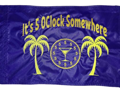 Alt Text: It's 5 OClock Somewhere safety flag with dense embroidered yellow text, palm trees, clock, and martini glass on blue nylon rectangle with solid brass grommets