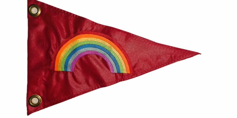 Rainbow safety flag with dense embroidered multi-color rainbow arch on red nylon pennant with solid brass grommets