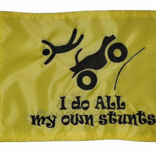 I Do All My Own Stunts ATV safety flag with embroidered flying rider and launching quad on safety yellow nylon rectangle with brass grommets
