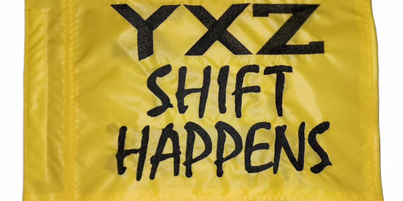 Yamaha YXZ Shift Happens safety flag with embroidered black lettering on yellow nylon rectangle with whip sleeve