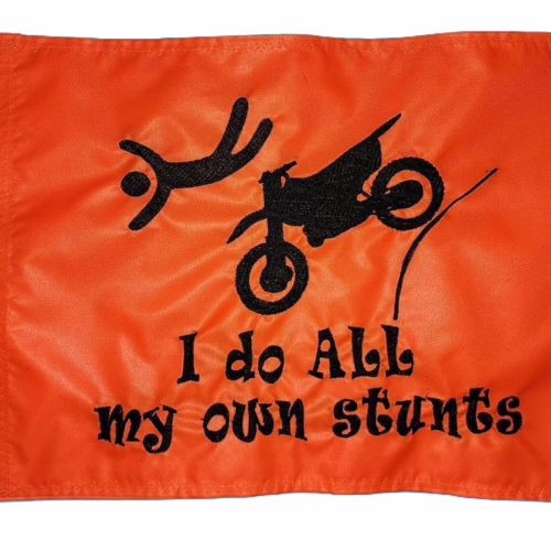 I Do All My Own Stunts dirt bike safety flag with embroidered flying rider and launching motorcycle on bright orange nylon rectangle with brass grommets
