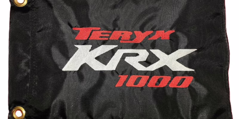 Kawasaki Teryx KRX 1000 safety flag with embroidered red and white logos on black nylon rectangle with brass grommets