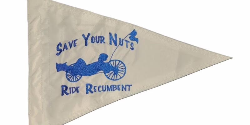 Save Your Nuts Ride Recumbent safety flag with embroidered blue recumbent rider and slogan on white nylon pennant with whip sleeve