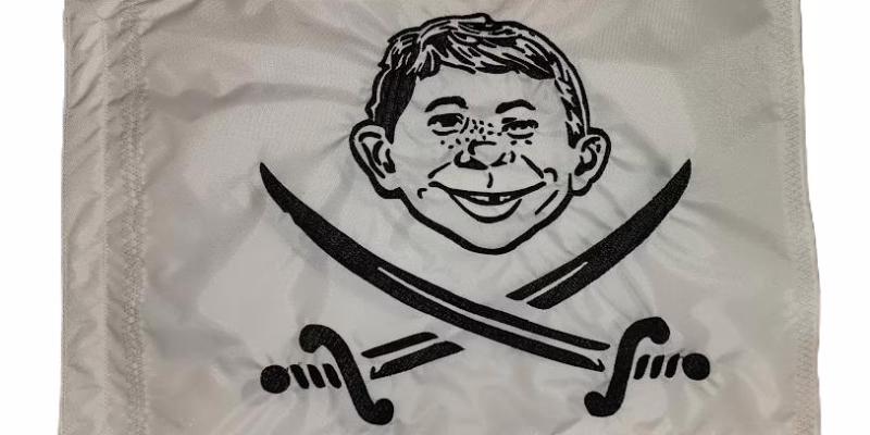 Alfred E. Neuman pirate safety flag with dense embroidered gap-toothed face and crossed swords on nylon rectangle with whip sleeve