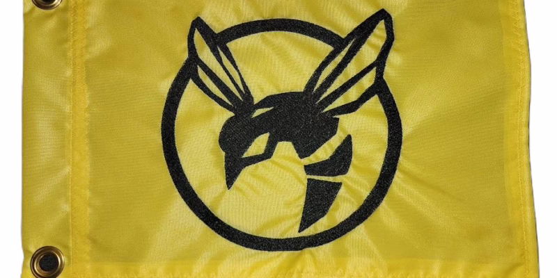 Alt Text: Yellow jacket encircled hornet safety flag with dense embroidered black hornet mascot inside a ring on yellow nylon rectangle with solid brass grommets
