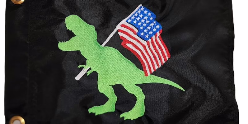 T-Rex holding American flag safety flag with dense embroidered green dinosaur and US flag on black nylon rectangle with solid brass grommets