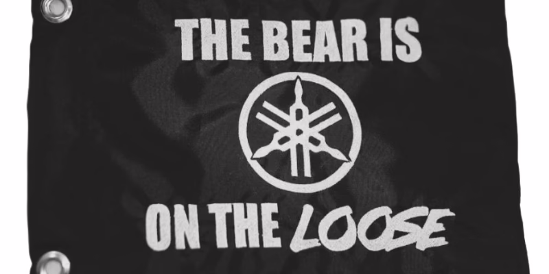 Personalized Yamaha safety flag with embroidered tuning forks emblem and The Bear Is On The Loose text on black nylon rectangle with brass grommets