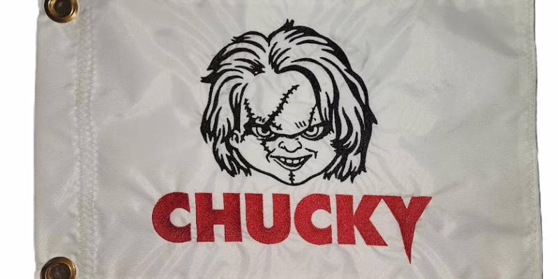Chucky safety flag with dense embroidered scarred doll face and red Chucky text on nylon rectangle with brass grommets