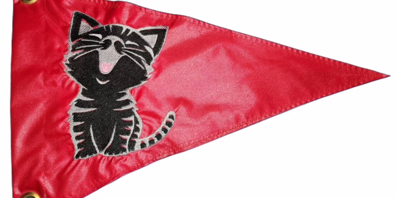 Smiling cat safety flag with dense embroidered black and grey tabby kitten on red nylon pennant with solid brass grommets
