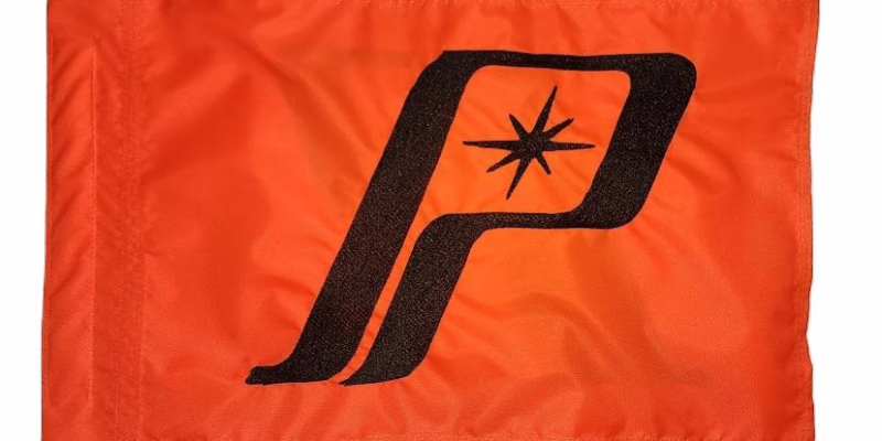 Polaris safety flag with embroidered black retro P star emblem on orange nylon rectangle with whip sleeve