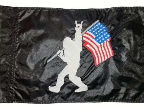 Rock On Bigfoot safety flag with embroidered white Sasquatch carrying American flag on black nylon rectangle with whip sleeve
