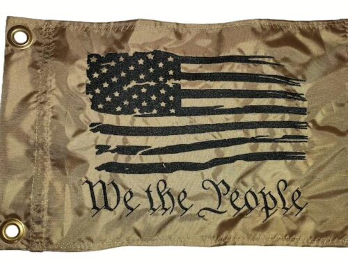 We the People safety flag with dense embroidered black tattered American flag and text on coyote tan nylon rectangle with solid brass grommets