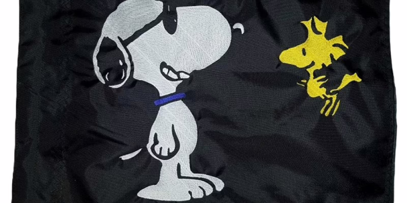 Snoopy and Woodstock safety flag with embroidered dog wearing sunglasses and yellow bird on black nylon rectangle with whip sleeve