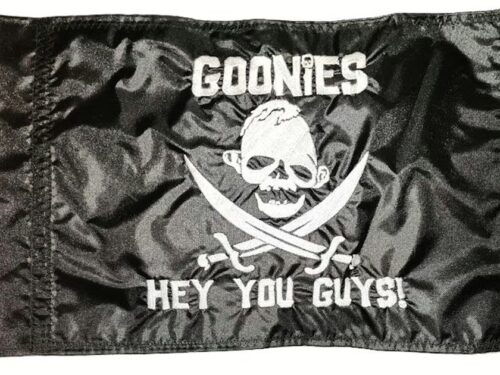 The Goonies Hey You Guys safety flag with dense embroidered silver skull emblem and movie quote text on black nylon rectangle with whip sleeve